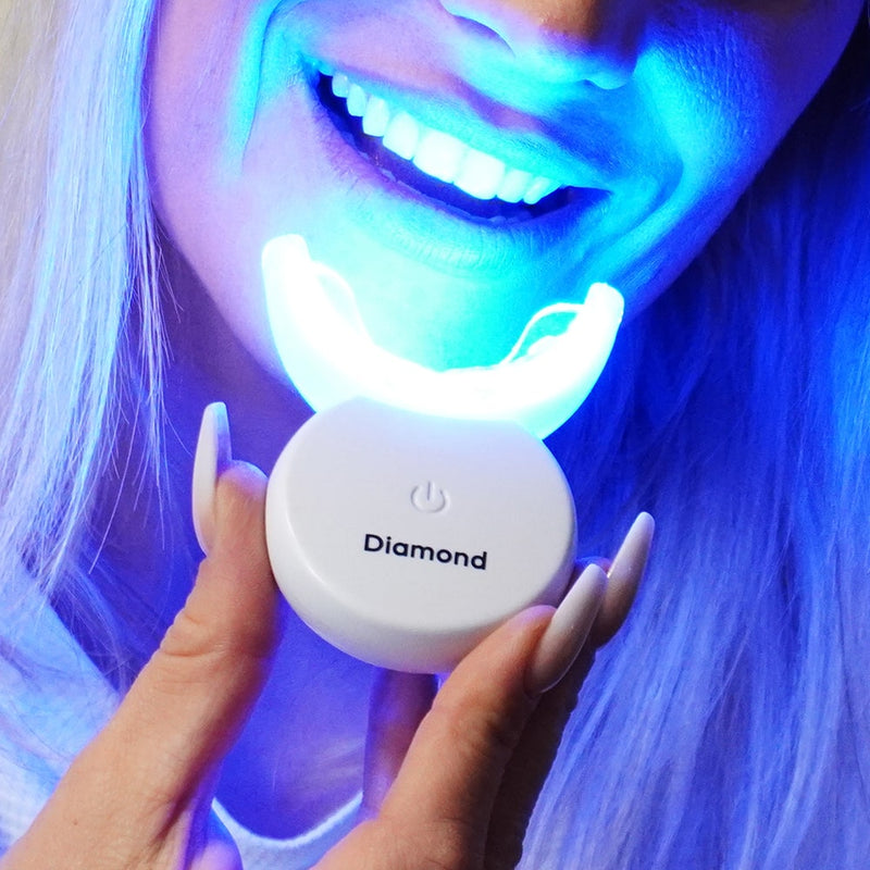 Paarse tandbleekset mondstuk met LED lamp in de hand van Diamond Smile